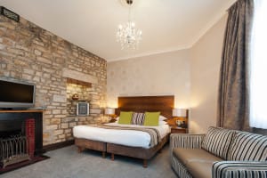 Large double bed with bedside tables and lamps on top, either side of the bed. The sofa is under the window faceing the fireplace which has the television on top of it.